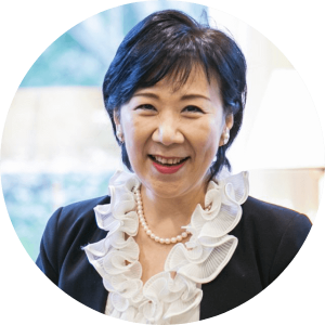 Ms. Akemi Aota, smiling, wearing a black jacket, white blouse, white pearl necklace